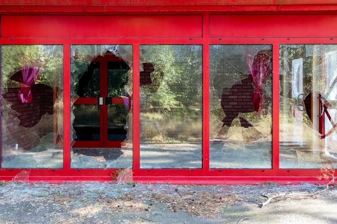 Trasiga röda skyltfönster med krossat glas